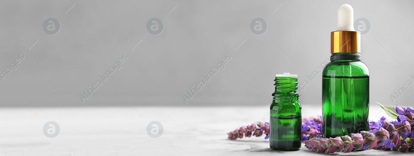 Image of Bottles of essential oil and flowers on table, space for text. Banner design