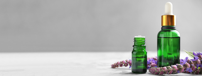 Bottles of essential oil and flowers on table, space for text. Banner design