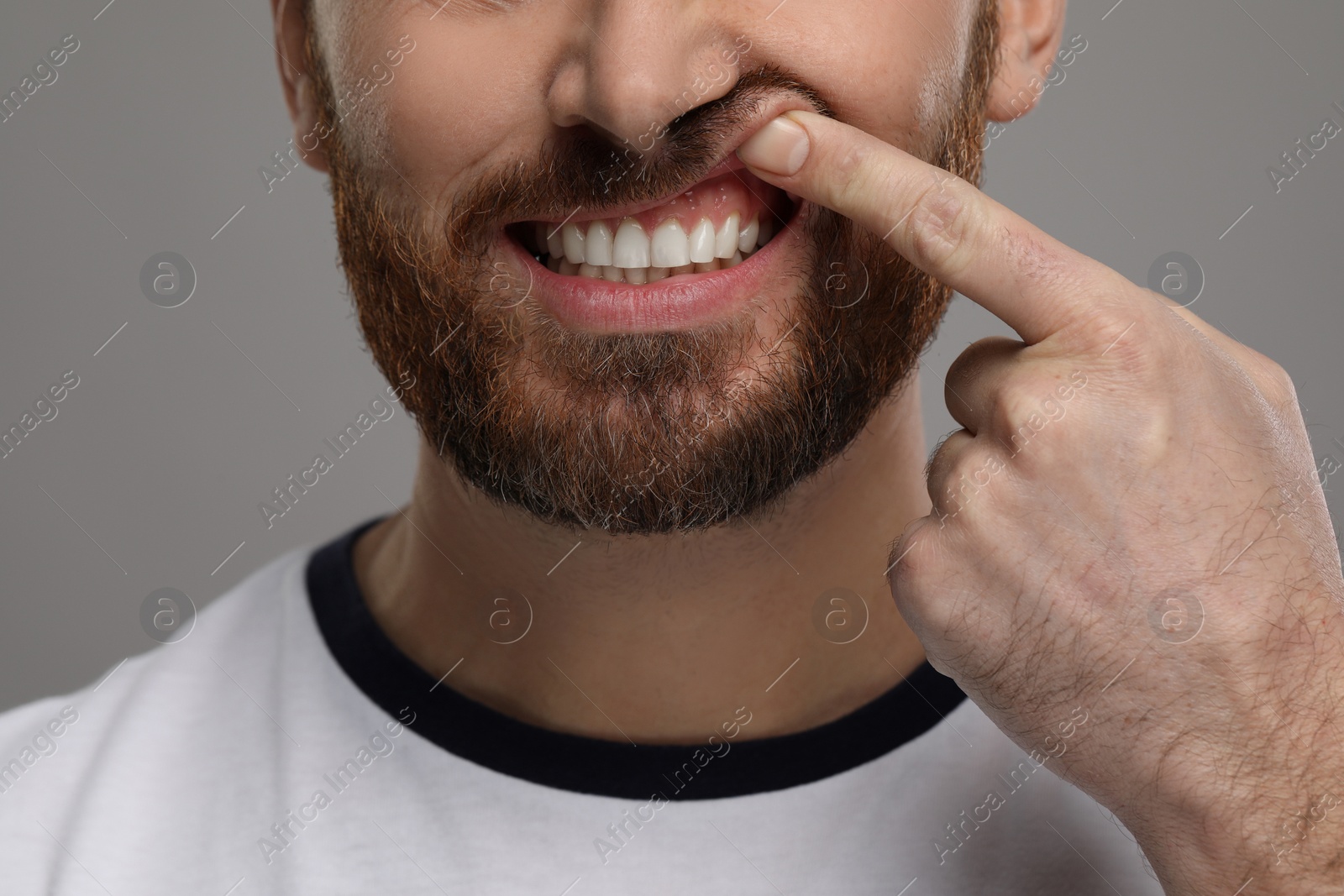 Photo of Man showing his healthy teeth and gums on grey background, closeup