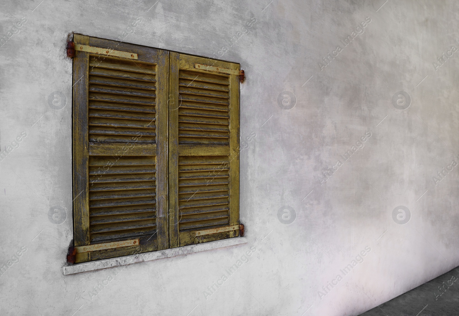 Photo of Window with old wooden shutters on concrete wall