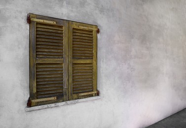 Window with old wooden shutters on concrete wall