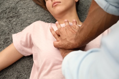 Photo of Man performing CPR on unconscious young woman indoors, top view. First aid