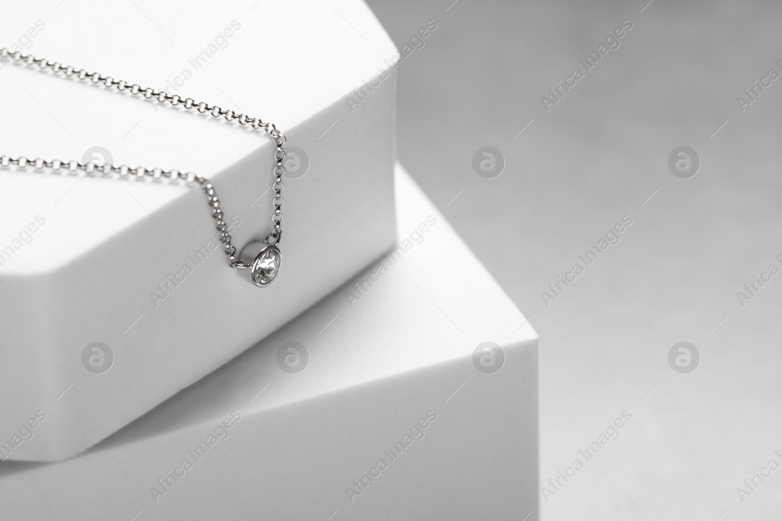 Photo of Beautiful necklace with gemstone on white podiums, space for text. Luxury jewelry
