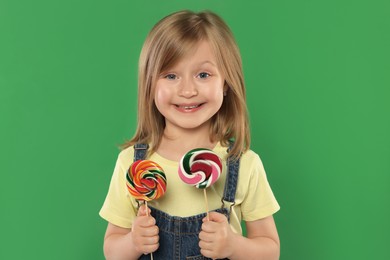 Portrait of happy girl with lollipops on green background