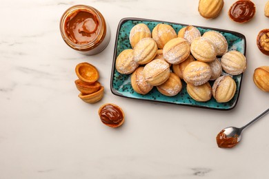 Photo of Homemade walnut shaped cookies with boiled condensed milk on white marble table, flat lay. Space for text