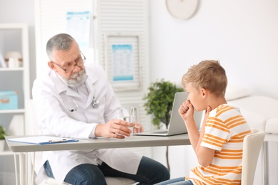 Photo of Coughing little boy visiting doctor at clinic