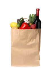 Photo of Paper bag with fresh vegetables and bottle of wine on white background