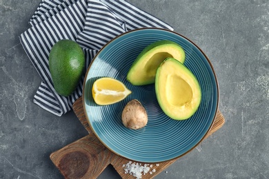 Flat lay composition with ripe avocados and lemon on grey background