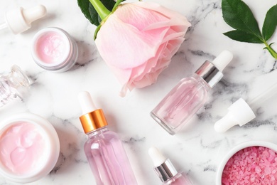 Flat lay composition with rose essential oil on marble table