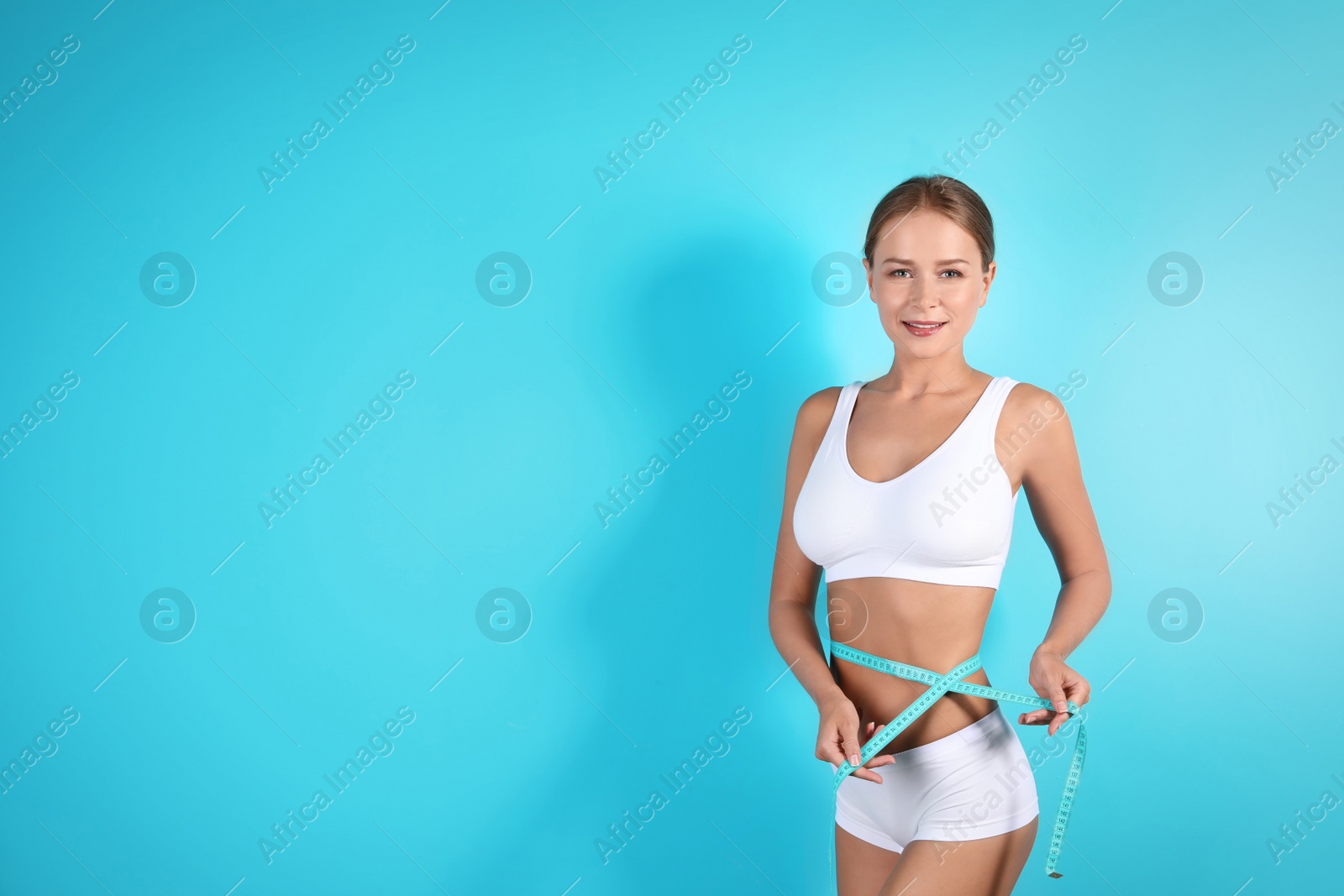 Photo of Slim woman with measuring tape on color background. Healthy diet