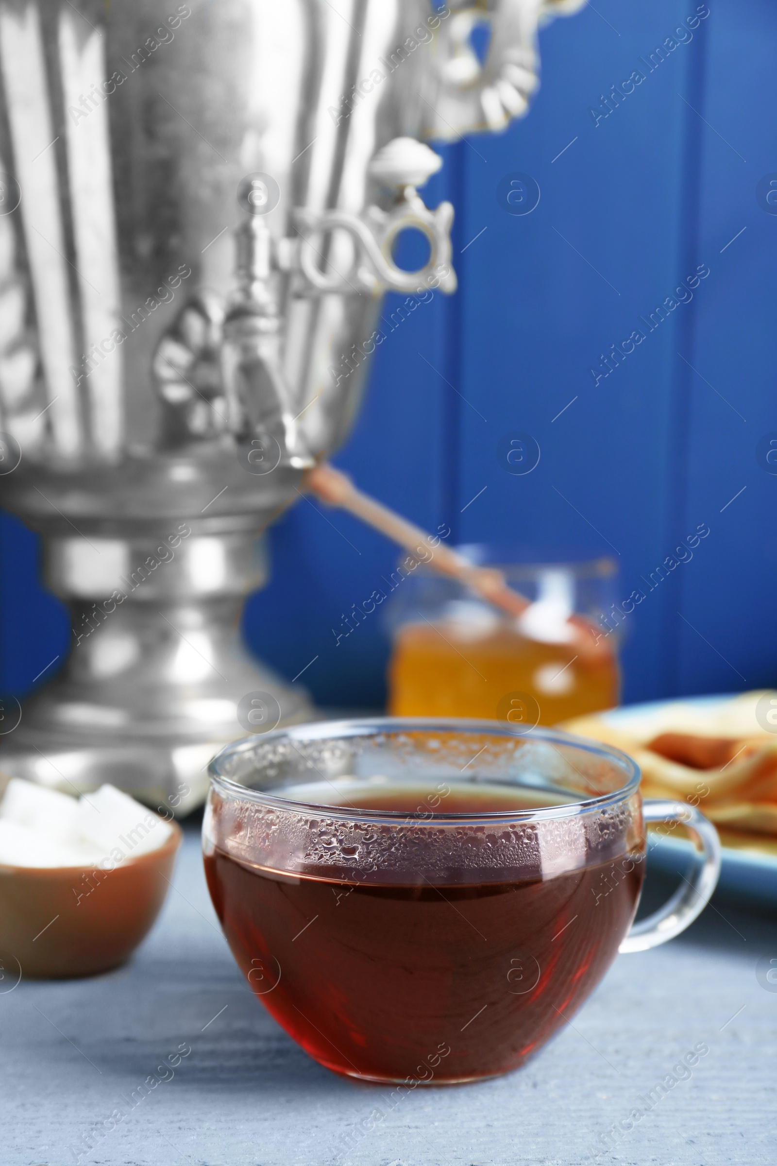 Photo of Glass cup of aromatic tea on light blue wooden table