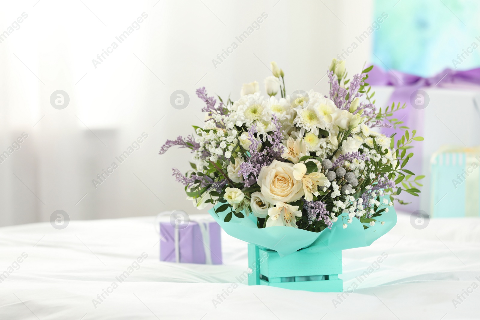 Photo of Beautiful bouquet of flowers in decorative crate on bed. Space for text