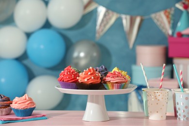 Photo of Different colorful cupcakes and party accessories on pink table