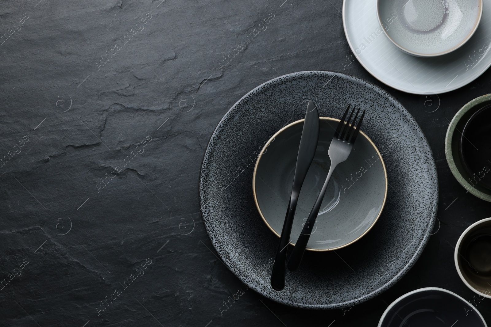 Photo of Set of clean tableware on black table, flat lay. Space for text