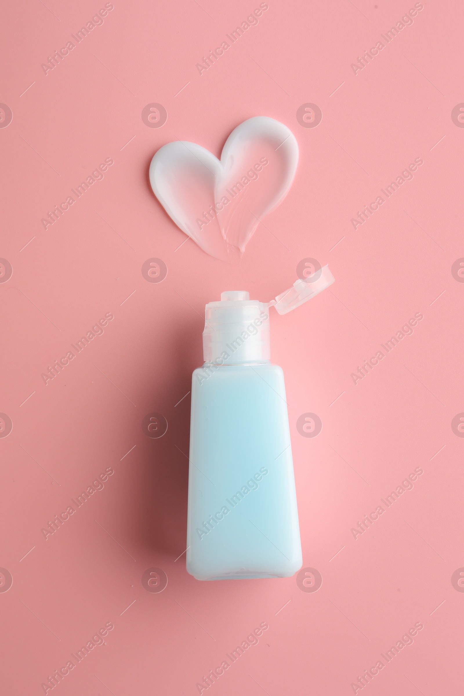 Photo of Tube and sample of facial cream on pink background, top view