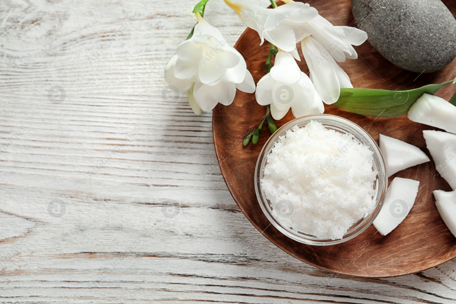 Photo of Glass bowl with natural coconut scrub on wooden tray