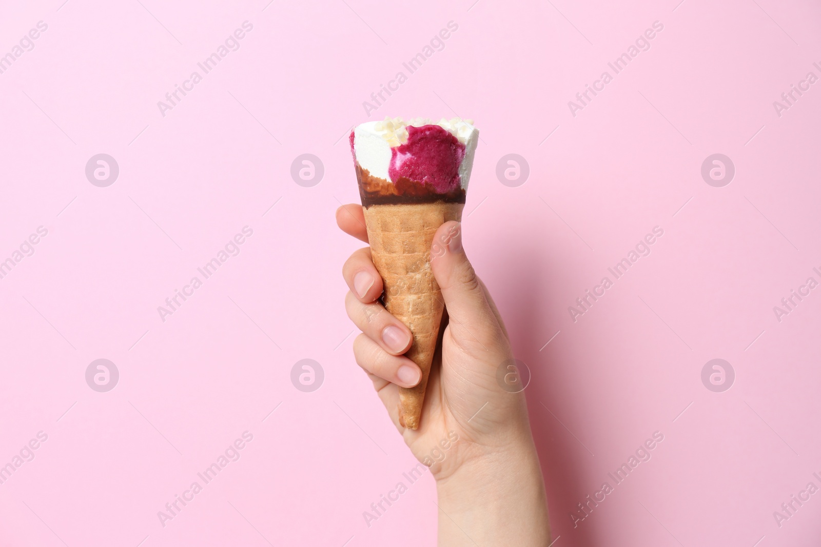 Photo of Woman holding waffle cone with delicious ice cream on color background