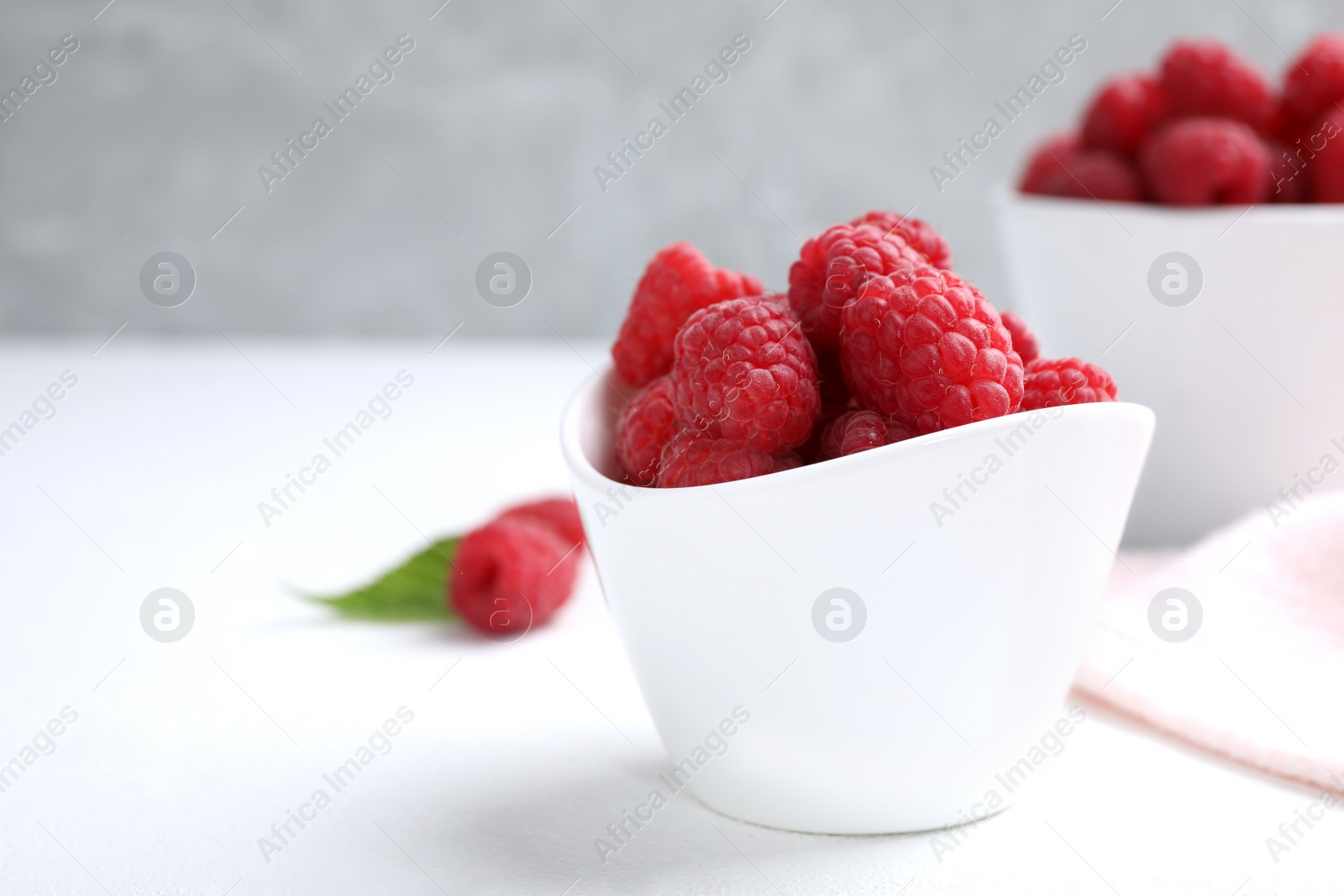 Photo of Delicious fresh ripe raspberries in bowl on white table