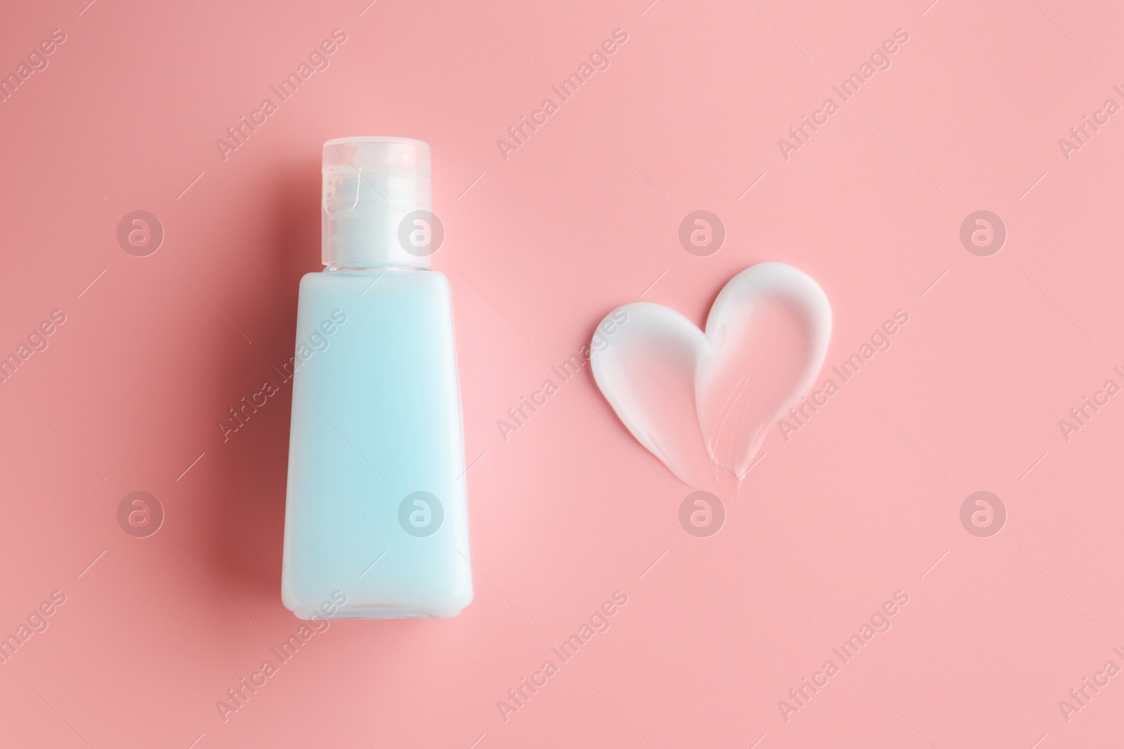 Photo of Tube and sample of facial cream on pink background, top view