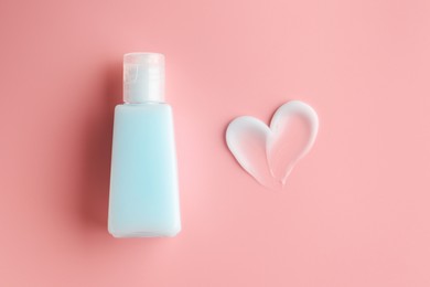 Tube and sample of facial cream on pink background, top view