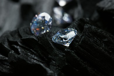 Photo of Beautiful shiny diamonds on coals, closeup view