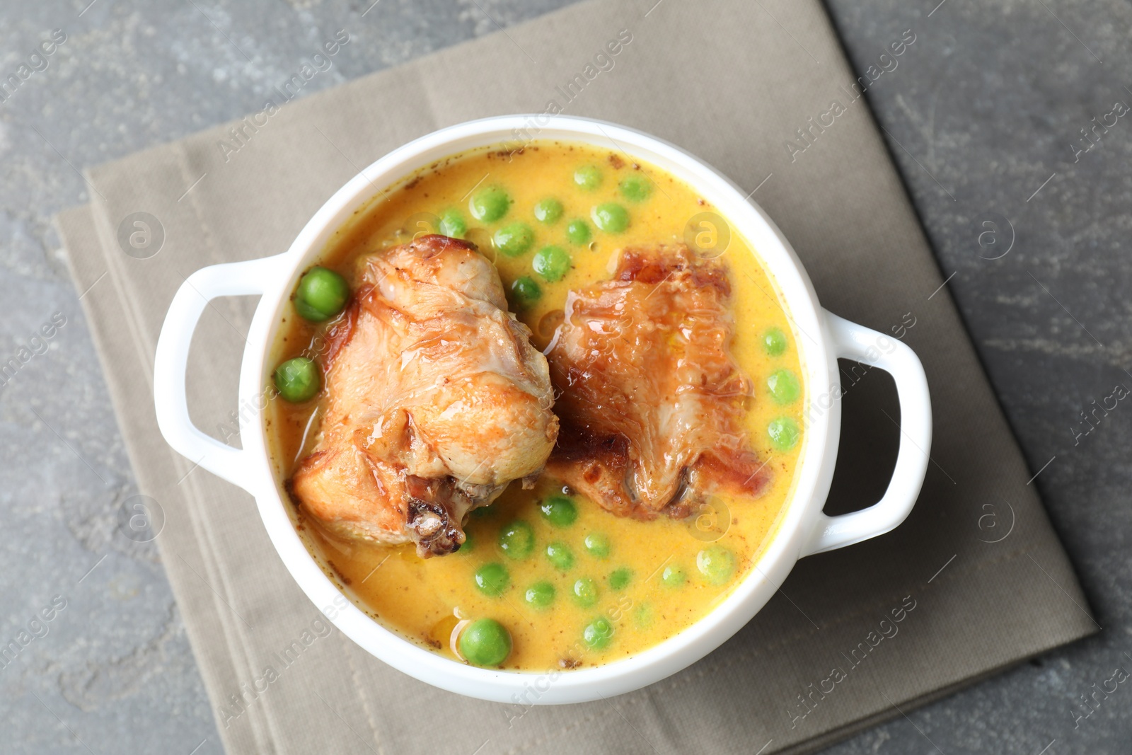 Photo of Tasty cooked rabbit meat with sauce and peas on grey table, top view