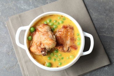Photo of Tasty cooked rabbit meat with sauce and peas on grey table, top view