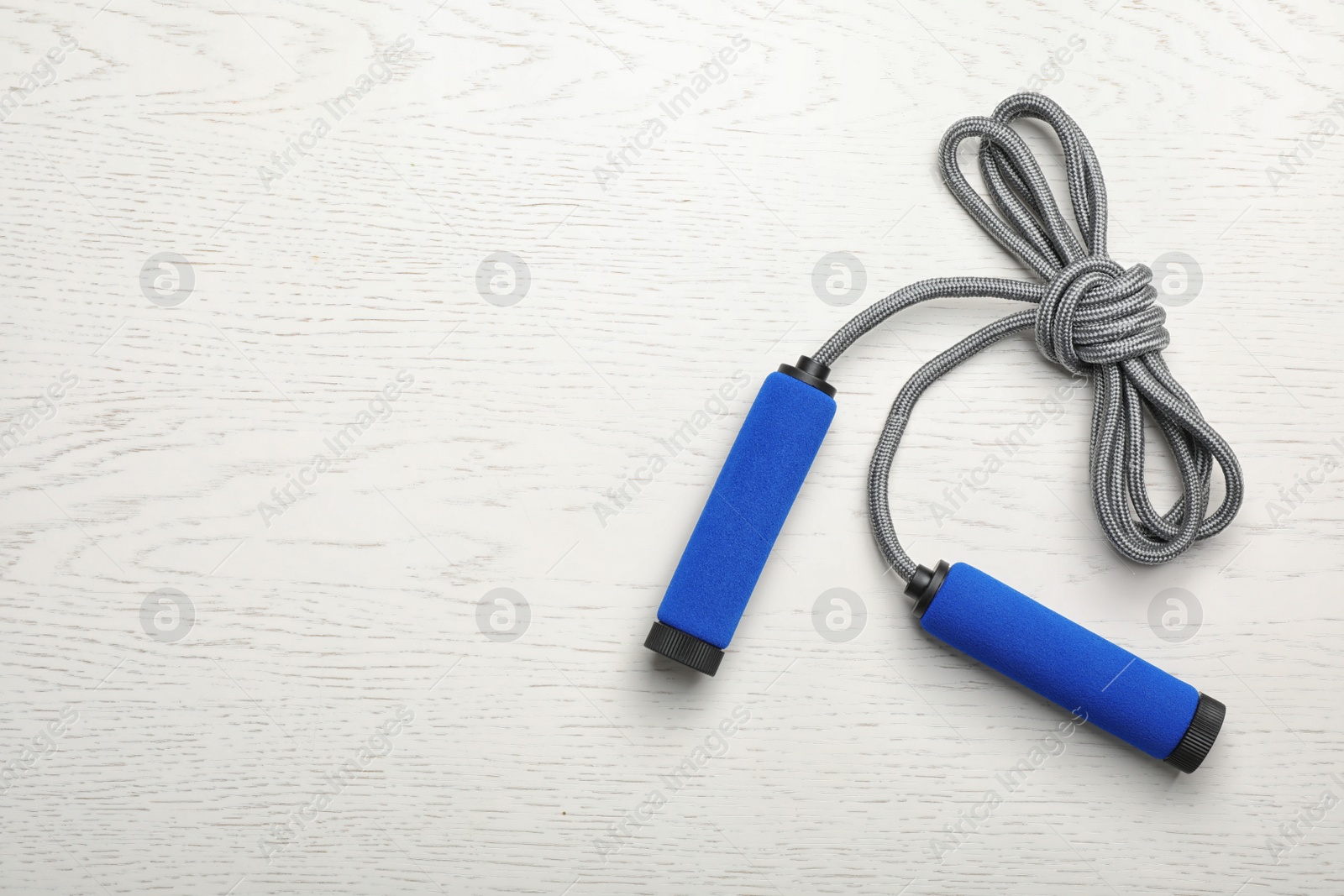 Photo of Jump rope and space for text on white wooden background, top view