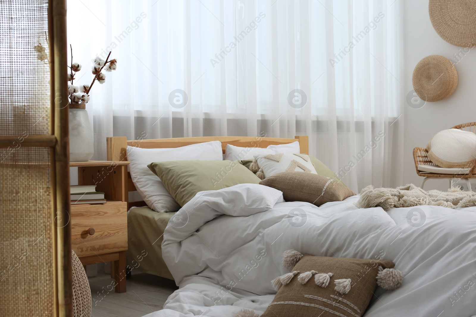 Photo of Large comfortable bed with soft pillows and duvet in room. Home textile