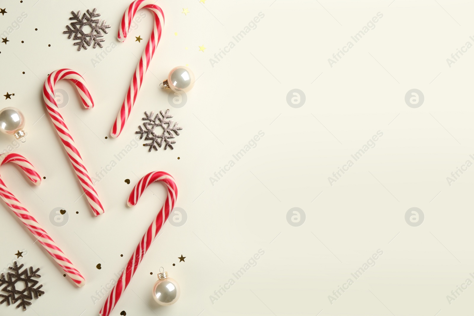 Photo of Candy canes, Christmas balls and snowflakes on beige background, flat lay. Space for text