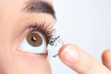 Young woman putting contact lens in her eye, closeup