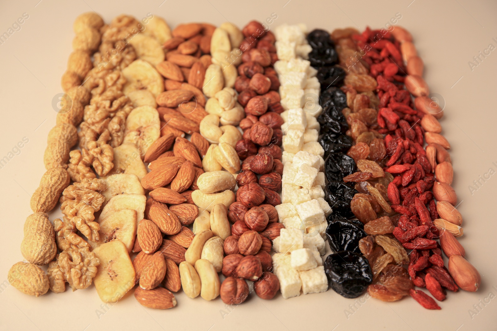 Photo of Different tasty nuts and dried fruits on beige background