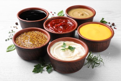 Photo of Many different sauces and herbs on white wooden table