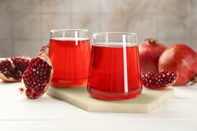 Photo of Tasty pomegranate juice in glasses and fresh fruits on white wooden table