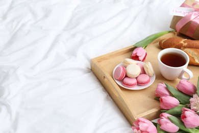 Photo of Delicious breakfast, flowers, gift box and card with phrase I Love You on bed, space for text