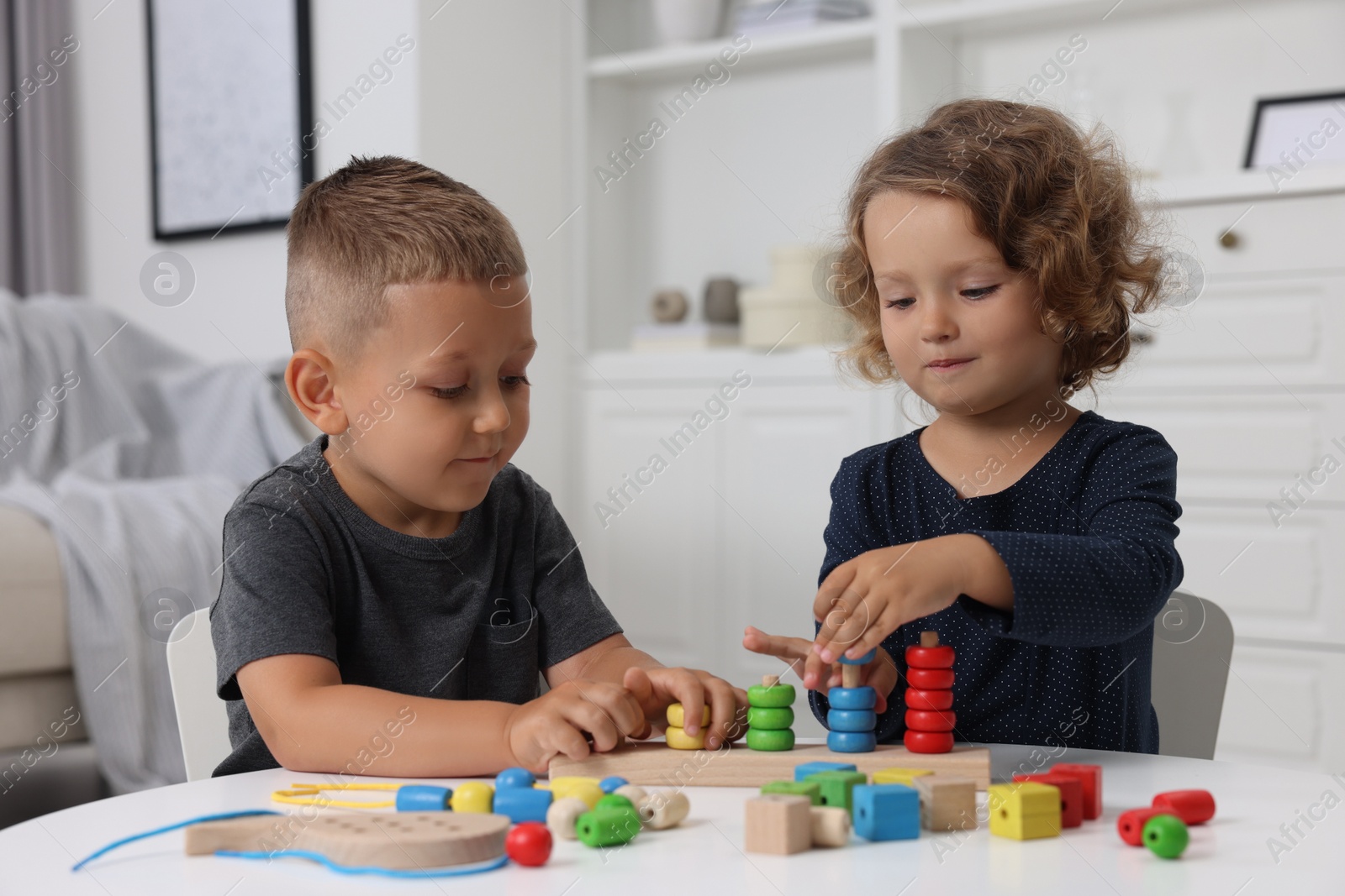 Photo of Motor skills development. Little kids playing with stacking and counting game at table indoors