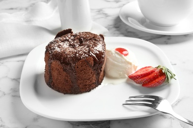 Photo of Plate of delicious fresh fondant with hot chocolate, ice cream and strawberry on table. Lava cake recipe