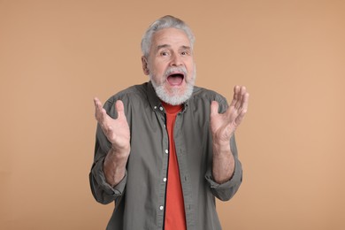 Portrait of surprised senior man on beige background