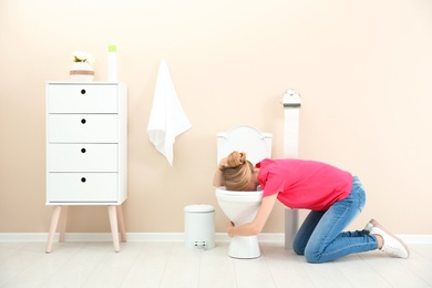 Photo of Young woman vomiting in toilet bowl at home