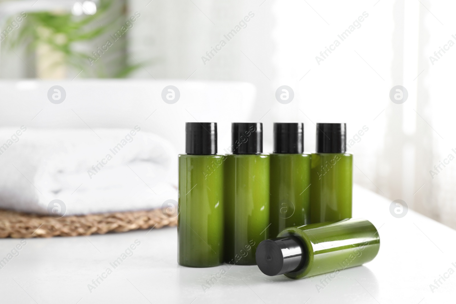 Photo of Mini bottles with cosmetic products on white table in bathroom. Space for text