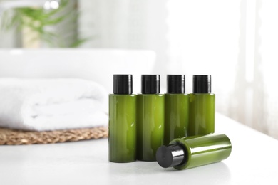 Mini bottles with cosmetic products on white table in bathroom. Space for text