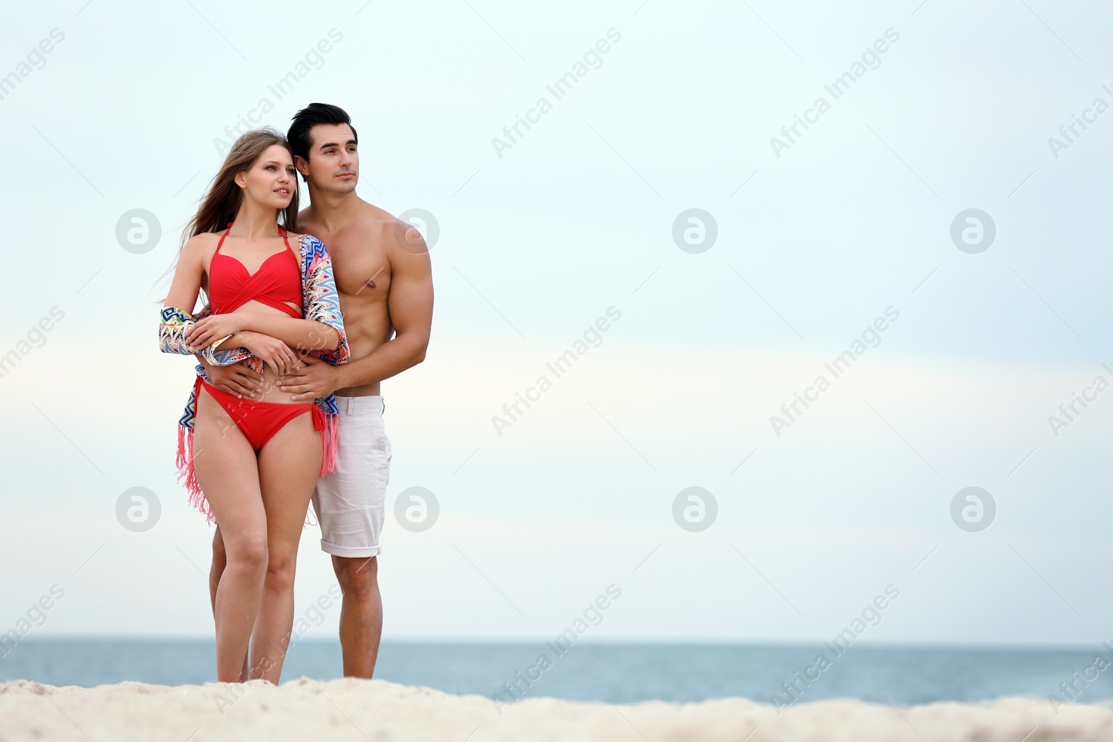 Photo of Happy young couple spending time together on sea beach. Space for text