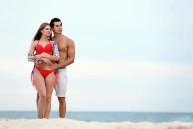 Photo of Happy young couple spending time together on sea beach. Space for text