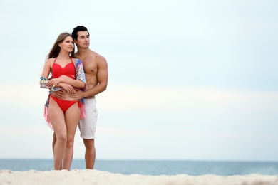 Happy young couple spending time together on sea beach. Space for text