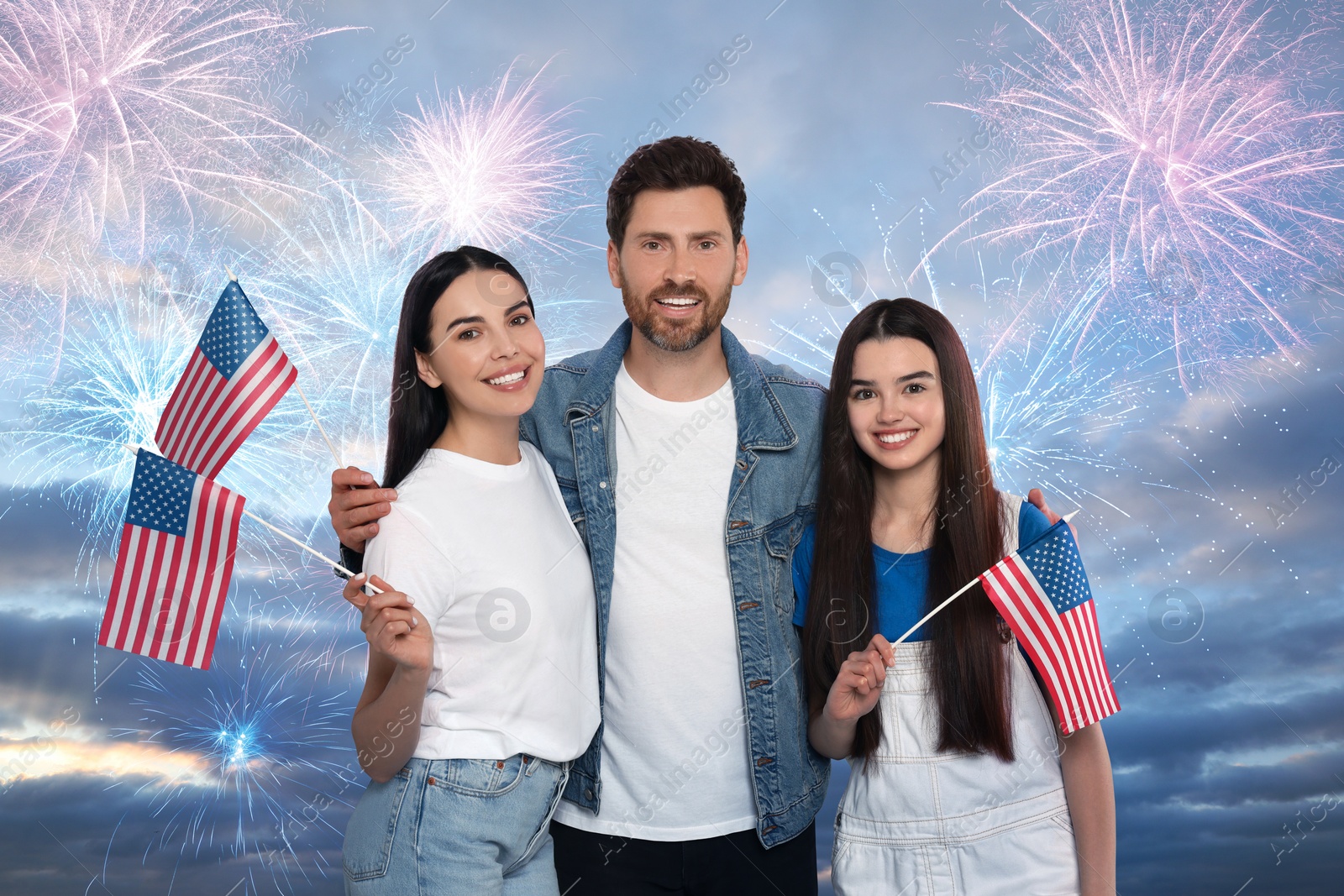 Image of 4th of July - Independence day of America. Happy family holding national flags of United States against sky with fireworks