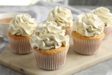 Tasty cupcakes with vanilla cream on grey table, closeup