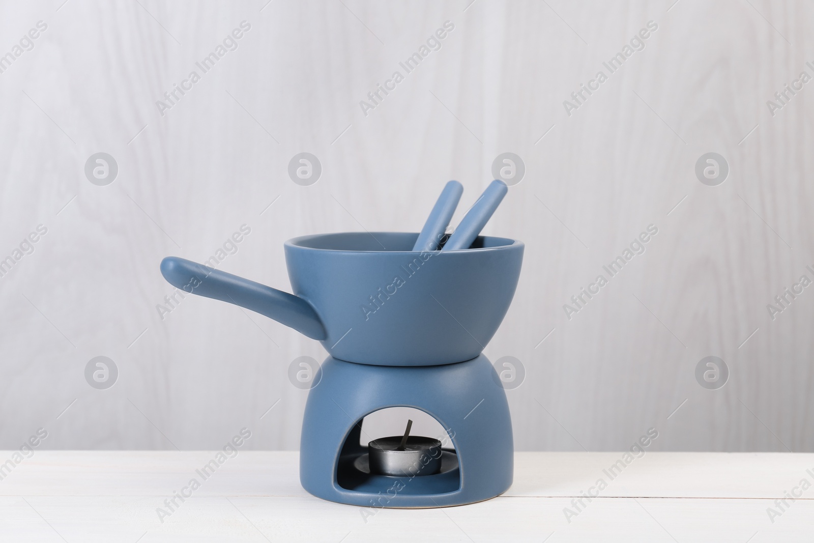 Photo of Fondue set on white wooden table. Kitchen equipment