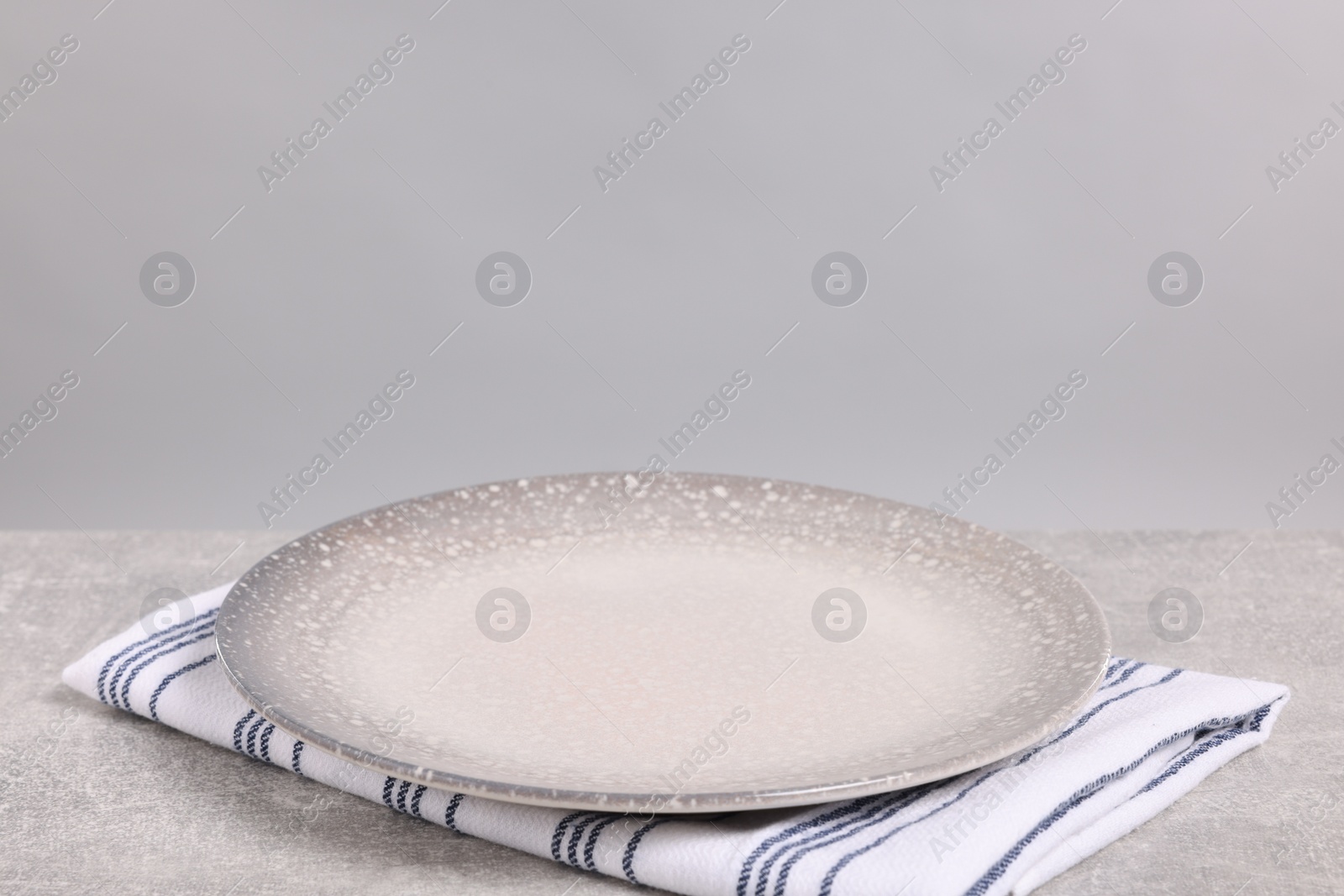 Photo of Empty ceramic plate on gray table against light background, space for text