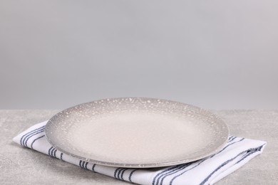 Empty ceramic plate on gray table against light background, space for text