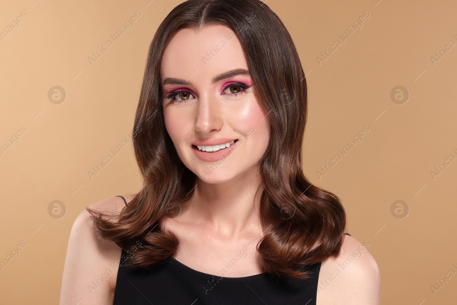 Photo of Portrait of beautiful young woman with makeup and gorgeous hair styling on beige background